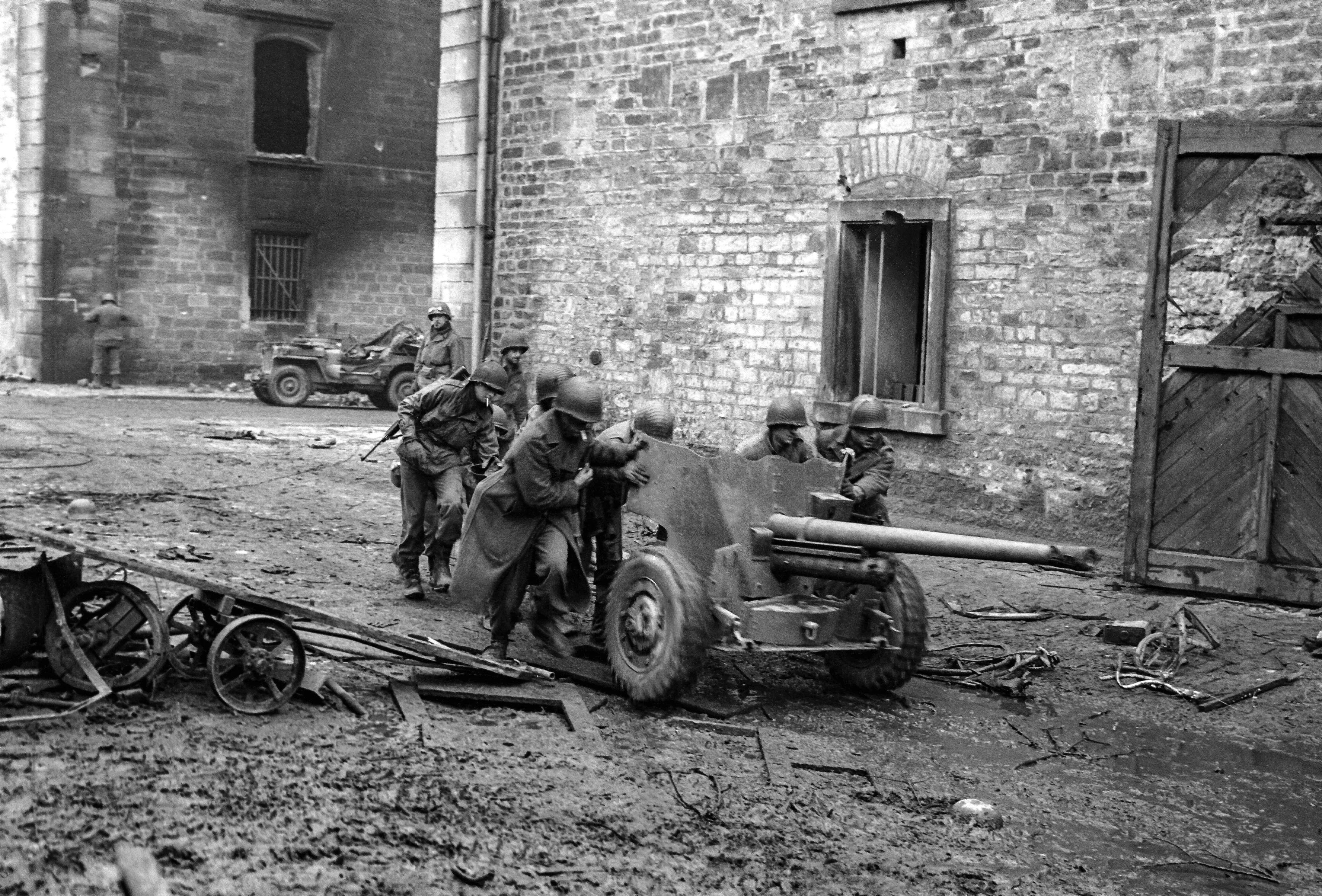 8th December 1944 TOPFOTO CODE: PD7486012 Artillery in street battle Saar Front. American gunners run a 57mm cannon into position down a street on the Saar front, during the advance of General Patton’s men across the Saar River. © Topfoto / Peter Deleuran | Used with exclusive permission.