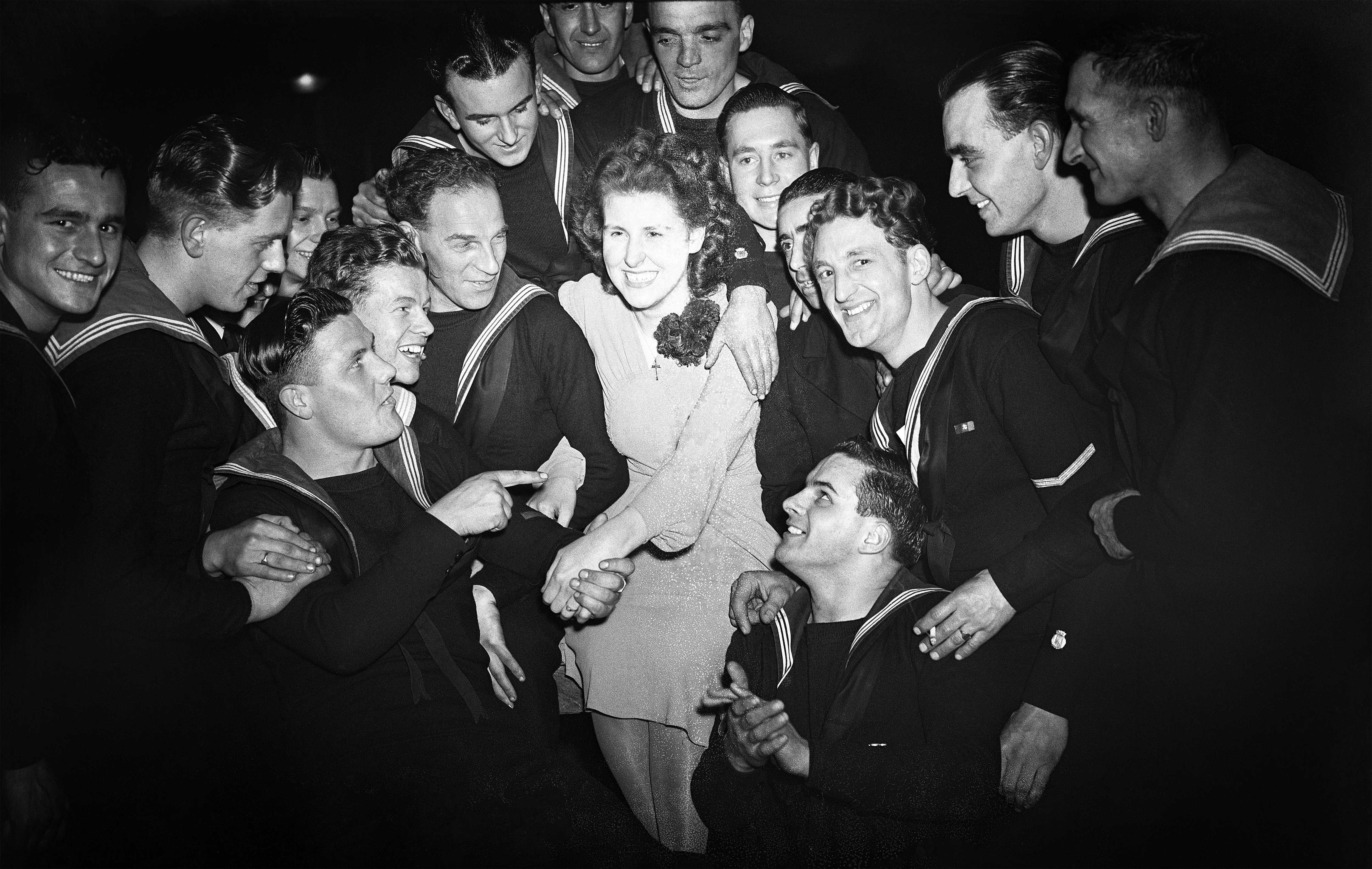 1st March 1945 TOPFOTO CODE: PD3001228 When Walthamstow, north-east London, entertained 150 officers and men of the minesweepers attached to H.M.S. ST. TUDNO, which the people ‘adopted’ three years ago, one of the principal items on the proceedings was the introduction to the ships’ companies of Miss Joan Butfield, from now on their own ‘pin-up girl’. PHOTO SHOWS:- ‘Pin-up girl’ Joan Butfield with some of her nautical admirers. © Topfoto / Peter Deleuran | Used with exclusive permission.