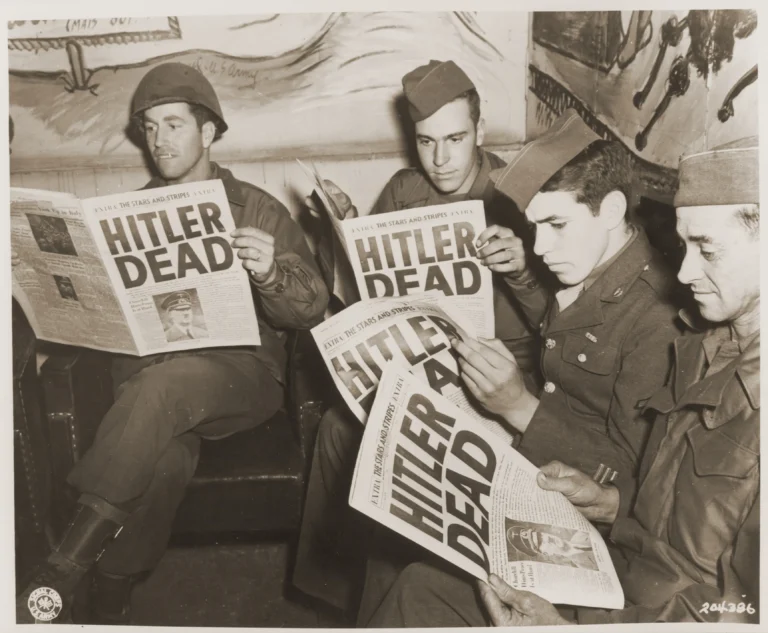 American soldiers read of Hitler's death in an "extra" edition of "Stars and Stripes." Pictured left to right: Pfc. Leonard A. Davis, Pfc. Richard Webster, Pfc. Julian Bellavance, and Pfc. Lex Hall.